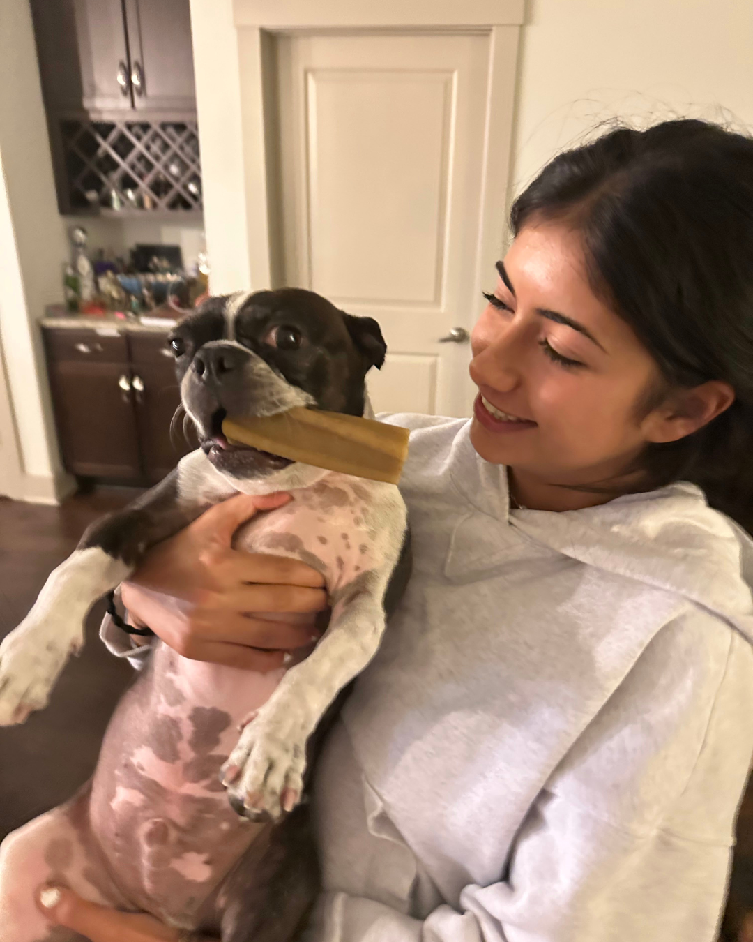 Benji being held by Melody with a bone in mouth!